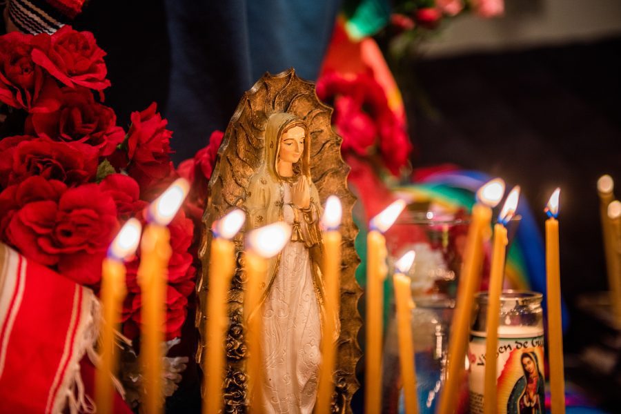 Small statue figures of the Virgin Mary and candles are lit at a church altar